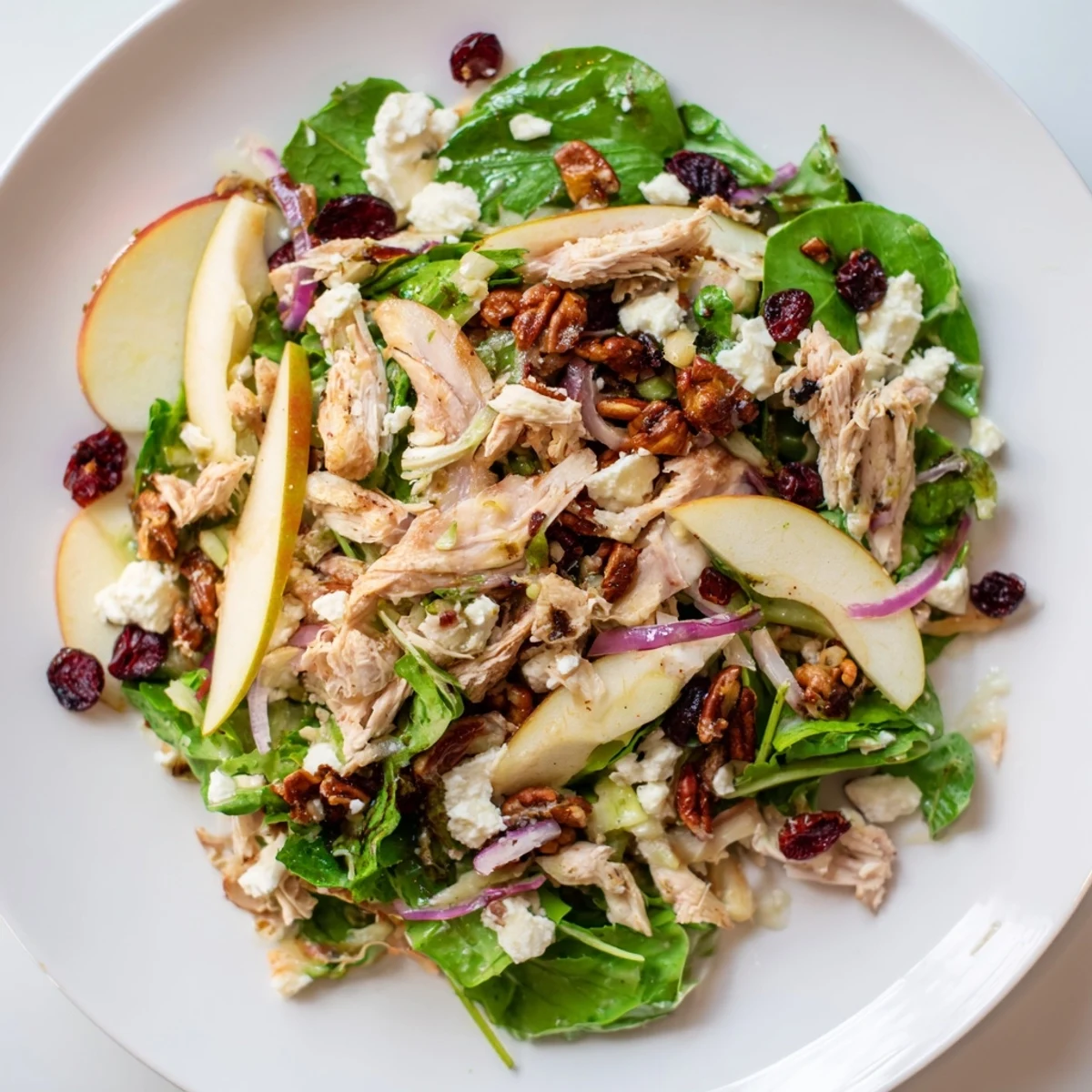 Vibrant Chicken and Apple Winter Salad with sliced apples, shredded chicken, and a drizzle of dressing.