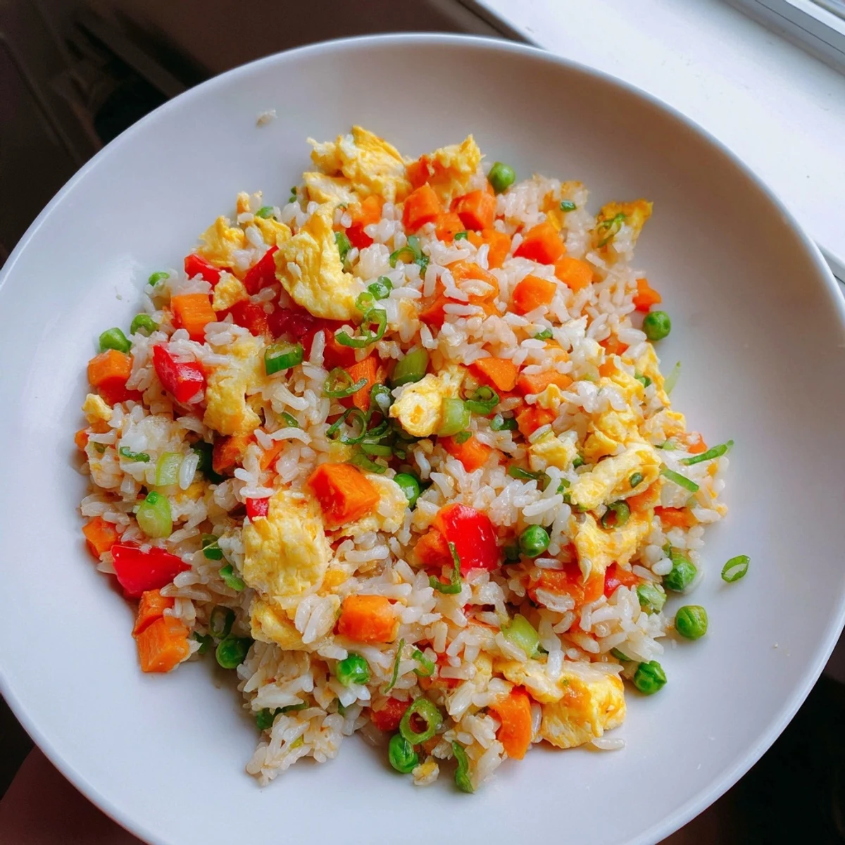 A delicious bowl of egg fried rice with peas and carrots, a quick weeknight dinner option.