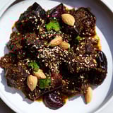 A steaming bowl of Moroccan Lamb Tagine, showcasing tender lamb, sweet prunes, and toasted almonds.