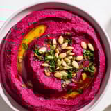 A creamy serving of beet hummus garnished with seeds and parsley, great flavor!