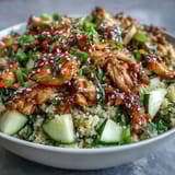 A plated bowl of Asian Sesame Chicken Couscous Salad features tender chicken and fresh cilantro. 
