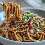 Spicy-sweet gochujang butter pasta with vibrant sauce clinging to linguine, topped with sliced green onions and sesame seeds.