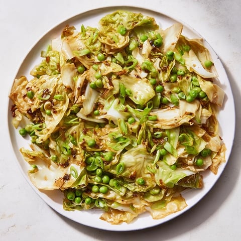 Steaming Cabbage Stir-Fry with Garlic tossed with vibrant green peas and savory soy sauce.