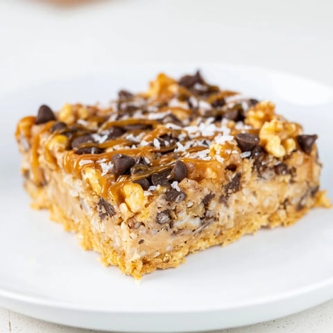 Golden, chewy 7-Layer Magic Bars topped with a glistening salted caramel drizzle, ready to enjoy.