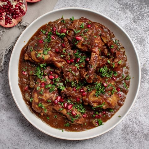 A steaming bowl of Pomegranate Walnut Fesenjan Stew with tender chicken thighs and rich sauce.