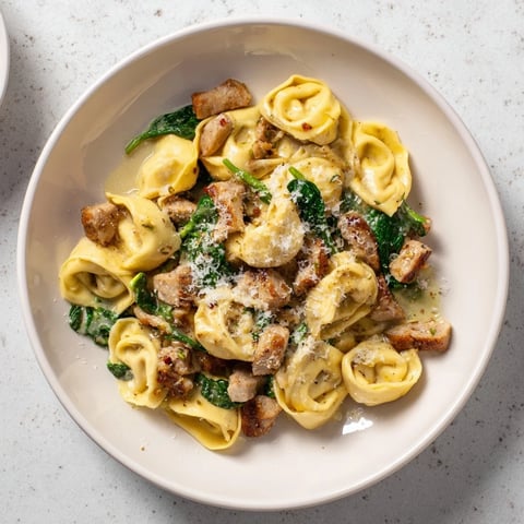 Creamy Chicken and Spinach Tortellini, a rich pasta dish with wilted spinach and grated Parmesan.