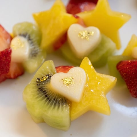 Vibrant, star-shaped strawberry and heart kiwi Midnight Kiss Cocktail garnishes for festive drink presentation.