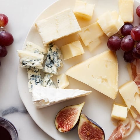 A beautiful Moments Magiques Plateau Bonne Année 2026 appetizer platter, overflowing with cheeses, fruits, and meats.