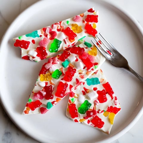Vibrant photo: scattered Gummy Bears and Candy Canes, a sweet topping on a white chocolate bark.