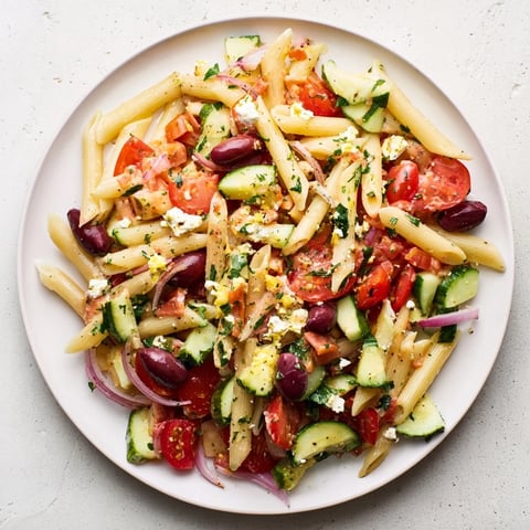 A colorful bowl of Mediterranean Pasta Salad with chickpeas, featuring feta and fresh vegetables.