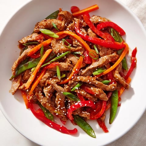 Sweet Teriyaki Pork Stir-Fry: a steaming bowl featuring tender pork and colorful vegetables, coated in glistening sauce.