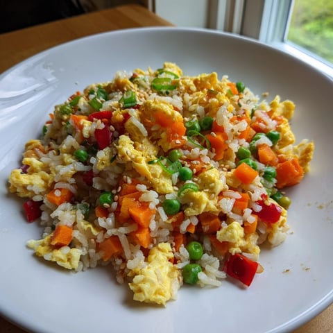 Golden, fluffy egg fried rice, showcasing vibrant vegetables and savory soy sauce, ready to eat.
