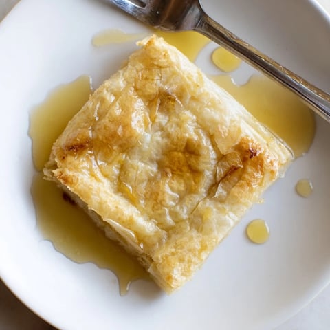 Golden-brown Moroccan Msemen pastry, flaky and crisp, is served warm and drizzled with honey.