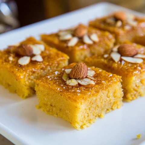 Golden, syrup-soaked Egyptian Basbousa cake with toasted almonds, a sweet, coconut-infused dessert.