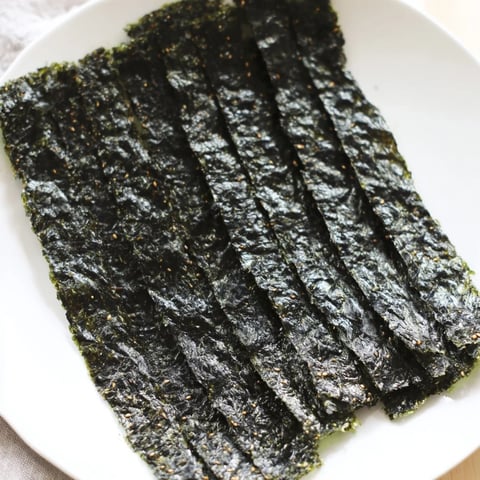 Golden, crispy Roasted Seaweed Chips, visibly dark green, seasoned with sesame oil and sea salt before baking.