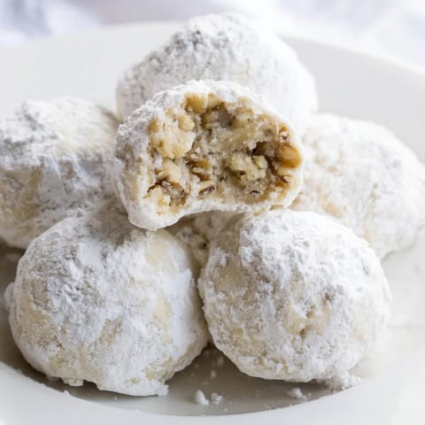 Freshly baked Budget-Friendly Snowball Cookies, golden-bottomed, ready to be rolled in a generous coating of sugar.