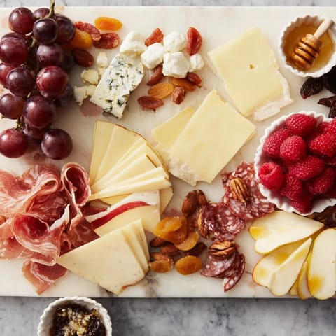 A delicious Lace & Pearls Elegant Board shows off artisan cheeses, charcuterie, and fresh fruit delights.