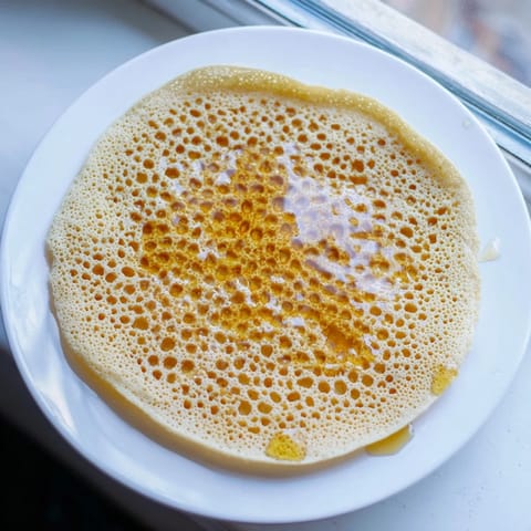 Homemade Moroccan Baghrir, a spongy pancake, shows off its delicate honeycomb texture beautifully in this photo.