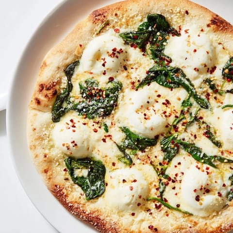 Slice of spinach ricotta pizza on a wooden board, topped with sautéed greens and herbs, perfect for a vegetarian Italian dinner.