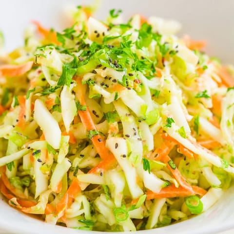 A bright bowl of Green Cabbage and Apple Slaw topped with poppy seeds.
