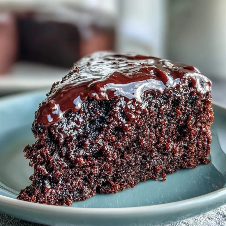 Homemade Easy Chocolate Fudge Cake with a thick chocolate glaze, ready to serve with a cup of coffee.