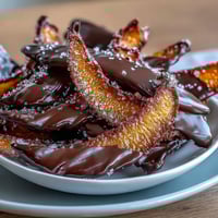 Candied orange peel dipped in dark chocolate, a zesty confection with glossy bittersweet coating and vibrant citrus aroma.