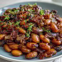 A hearty skillet of baked beans with crispy bacon and sweet brown sugar sauce, perfect for summer BBQs.