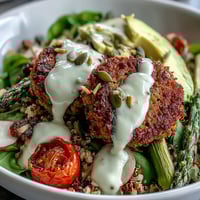 Spring Buddha Bowl with roasted asparagus, radishes, and crispy falafel, drizzled with zesty lemon-tahini dressing.